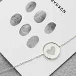 The Danibydsgn Heart Fingerprint Coin Bracelet in 925 Sterling Silver displayed beside fingerprint samples — showcasing the personalised engraving process that transforms real prints into a heart-shaped keepsake of love and memory.