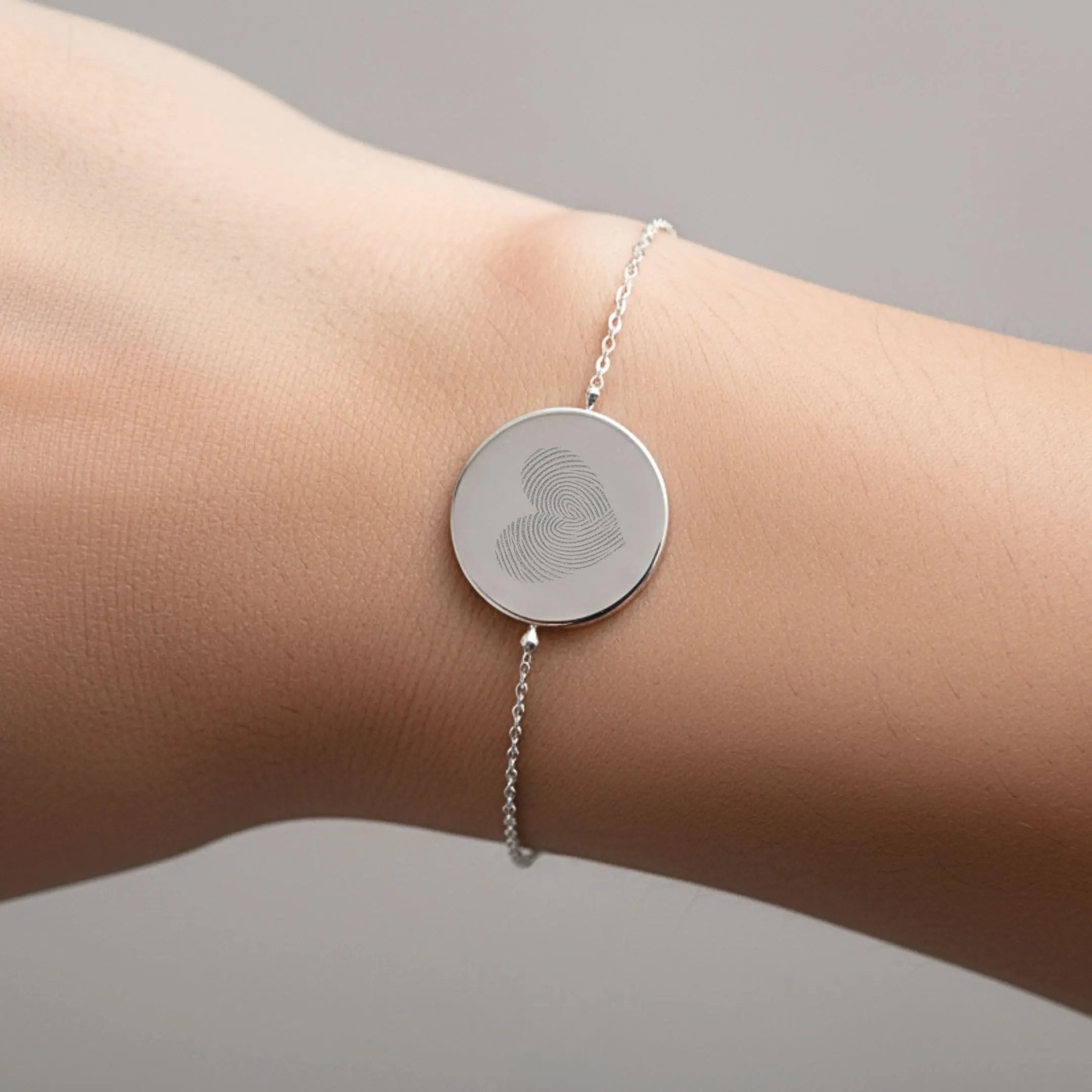 Heart fingerprint coin bracelet in 925 sterling silver worn on a wrist, showcasing unique design by Danibydsgn.