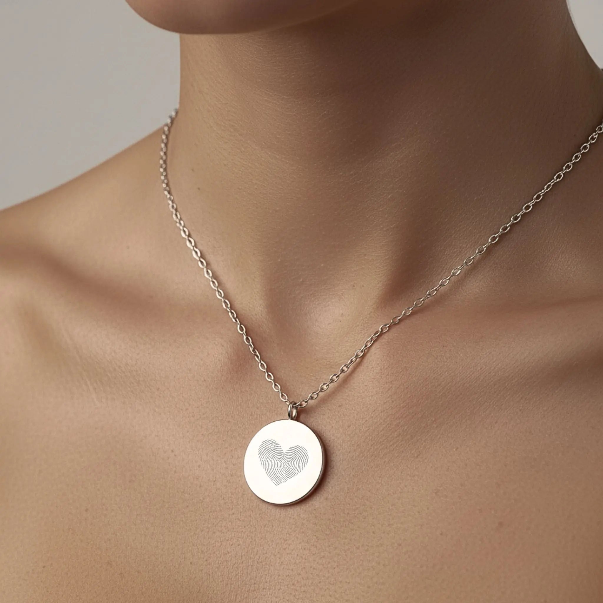 The Danibydsgn Heart Fingerprint Coin Necklace in 925 Sterling Silver worn on the neckline — showcasing its minimalist elegance and engraved heart-shaped fingerprint design, symbolising love and lasting connection.
