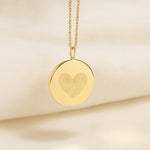 Elegant Heart Fingerprint Pendant Necklace in 18K Gold Vermeil by Danibydsgn resting on soft cream fabric. Features two fingerprints forming a heart design, symbolising love, unity, and connection. A luxury personalised keepsake necklace crafted with timeless minimalism and fine detail.