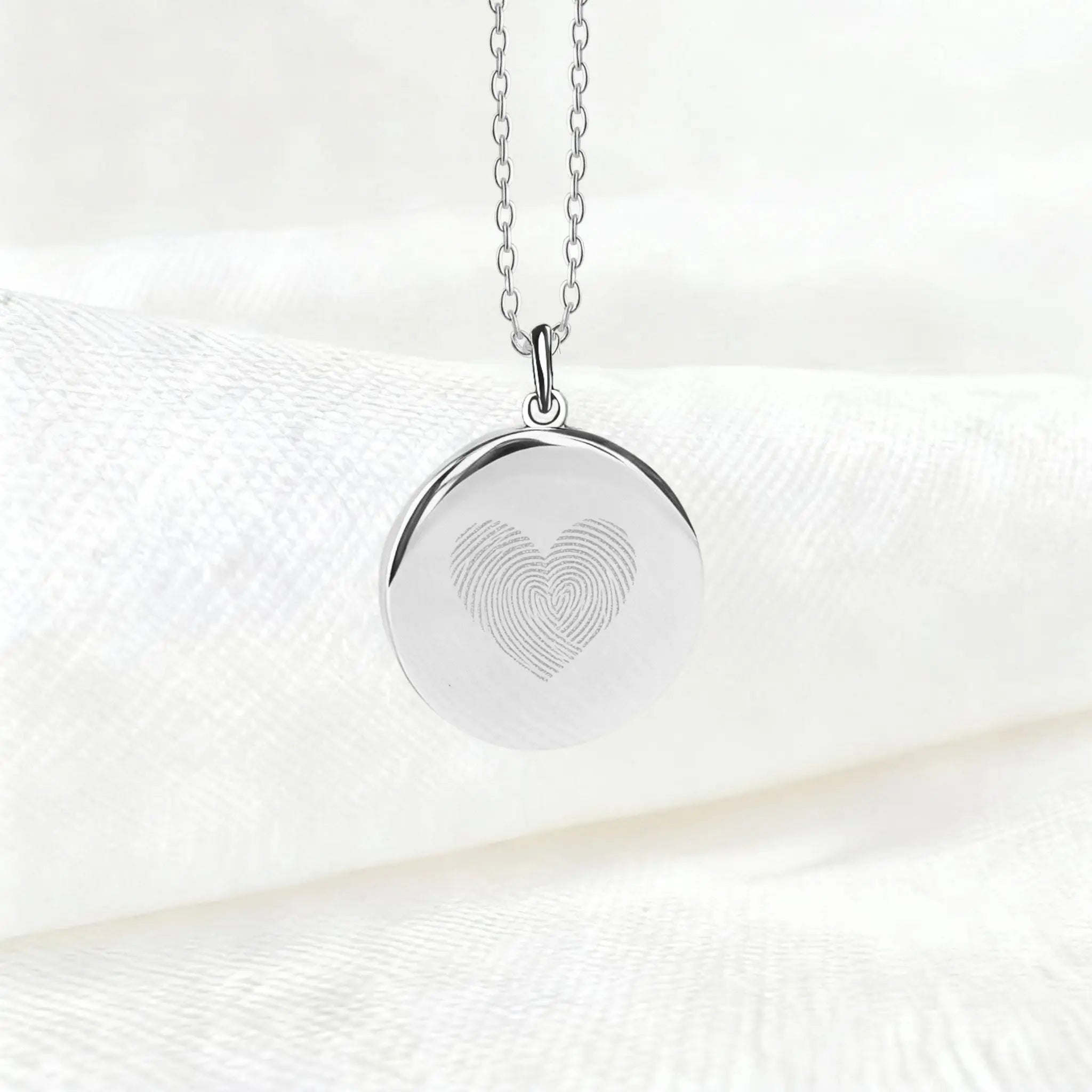 Danibydsgn Heart Fingerprint Pendant Necklace in 925 Sterling Silver displayed on soft white fabric, featuring two fingerprints elegantly engraved to form a heart — a minimalist and meaningful symbol of love and connection.