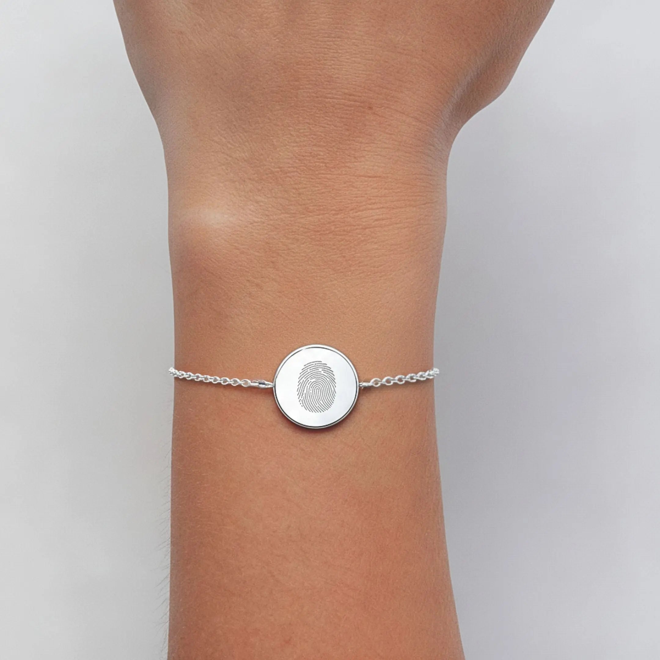Single fingerprint coin bracelet in 925 sterling silver worn on a wrist, showcasing intricate design by Danibydsgn.