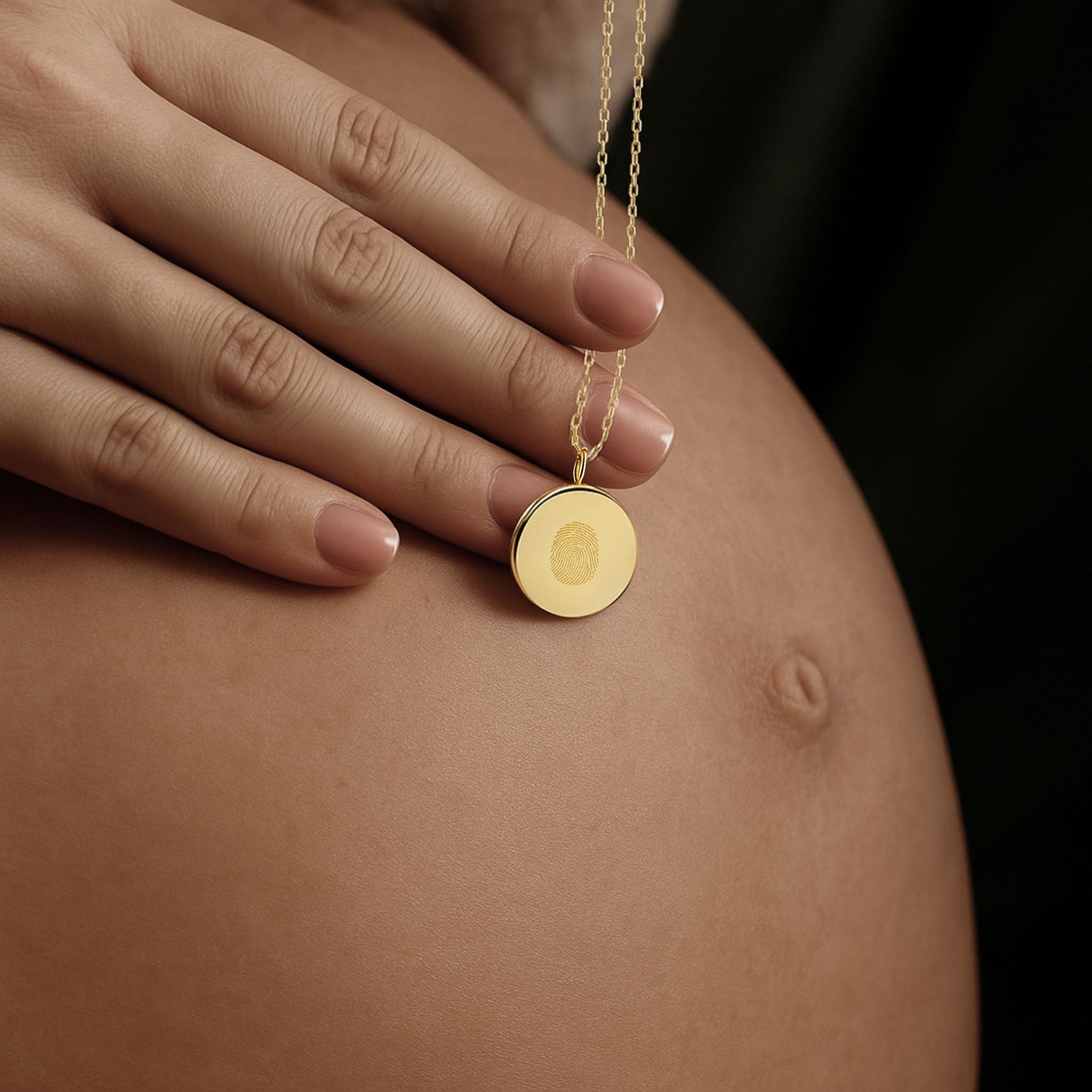 An intimate moment captured as a mother gently rests her hand on her baby bump while holding the Danibydsgn Single Fingerprint Coin Necklace in 18K Gold Vermeil. The pendant features one delicately engraved fingerprint, symbolising a mother’s everlasting connection to her child — a timeless keepsake of love, anticipation, and new beginnings.