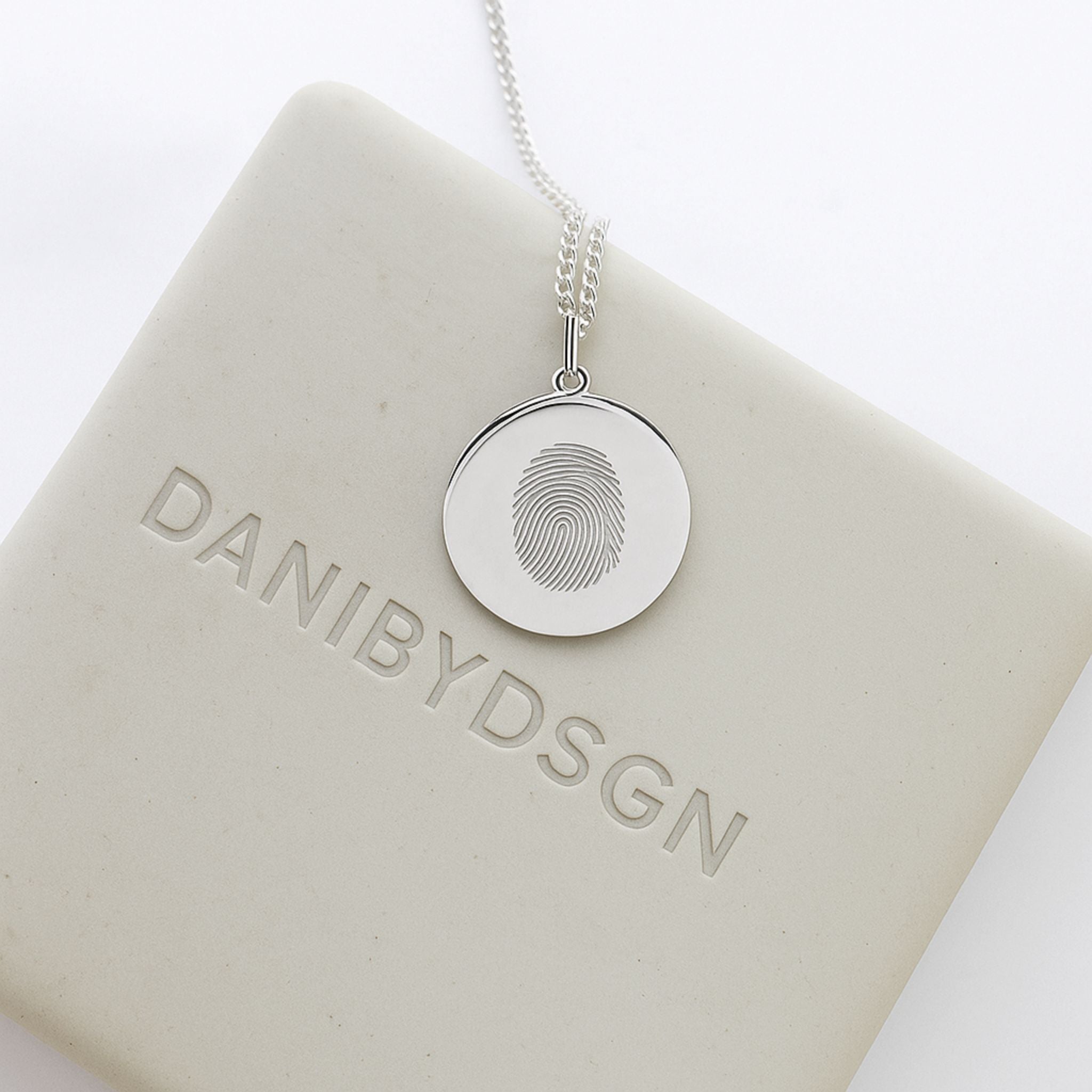 Danibydsgn Single Fingerprint Pendant Necklace in 925 Sterling Silver displayed on branded packaging — showcasing the intricate engraved fingerprint design and minimalist luxury craftsmanship that defines personalized keepsake jewelry.