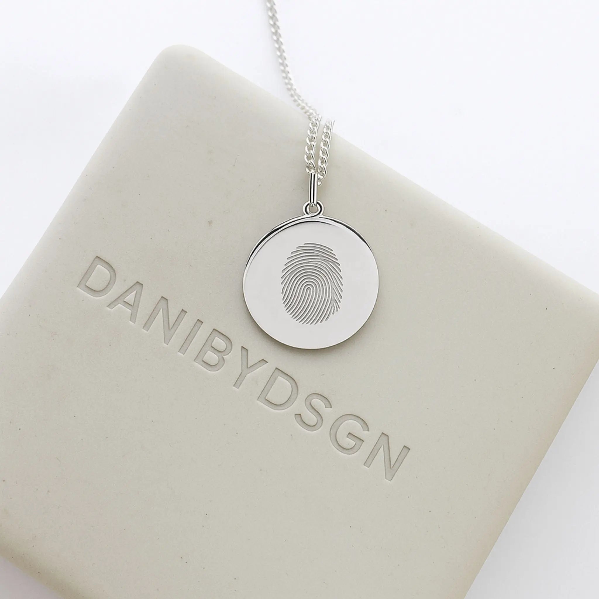 Danibydsgn Single Fingerprint Pendant Necklace in 925 Sterling Silver displayed on branded packaging — showcasing the intricate engraved fingerprint design and minimalist luxury craftsmanship that defines personalized keepsake jewelry.