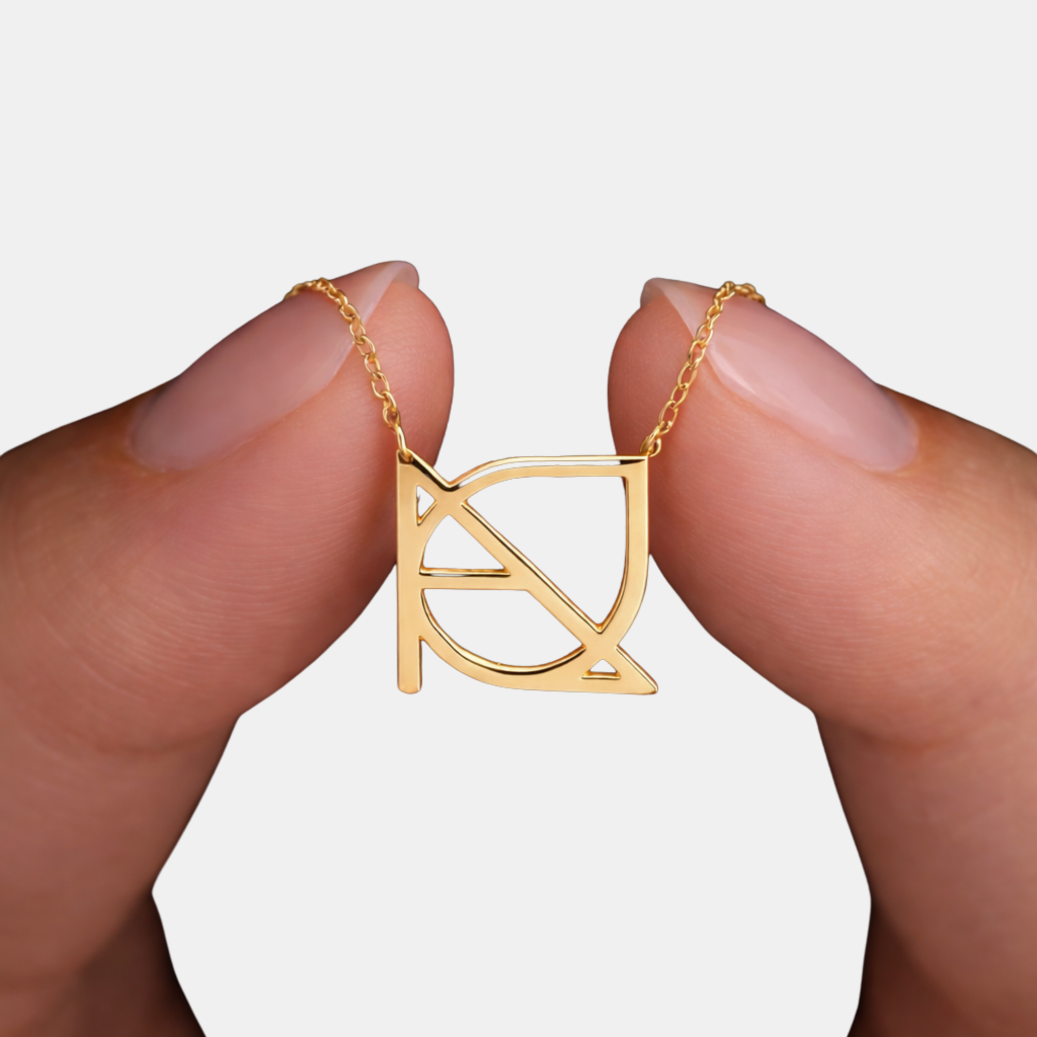 A close-up shot of fingers holding a custom necklace in 9k gold, highlighting a minimalist jewelry piece featuring a hand-designed Danibydsgn symbol cut out jewelry pendant with a distinct side-welded chain style.
