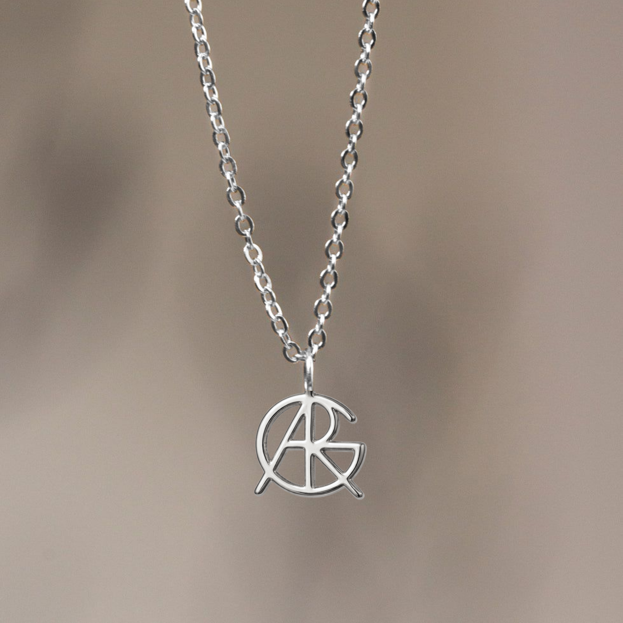 Close-up of a custom necklace made from 925 sterling silver, showcasing a meaningful jewelry piece featuring a unique hand-designed Danibydsgn symbol cut out jewelry pendant hanging on a fine chain.