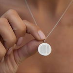 Close-up of a person holding the Danibydsgn Three Fingerprint Pendant Necklace in 925 Sterling Silver, showing three engraved fingerprints on a polished round coin pendant — a personalized symbol of love, memory, and connection.