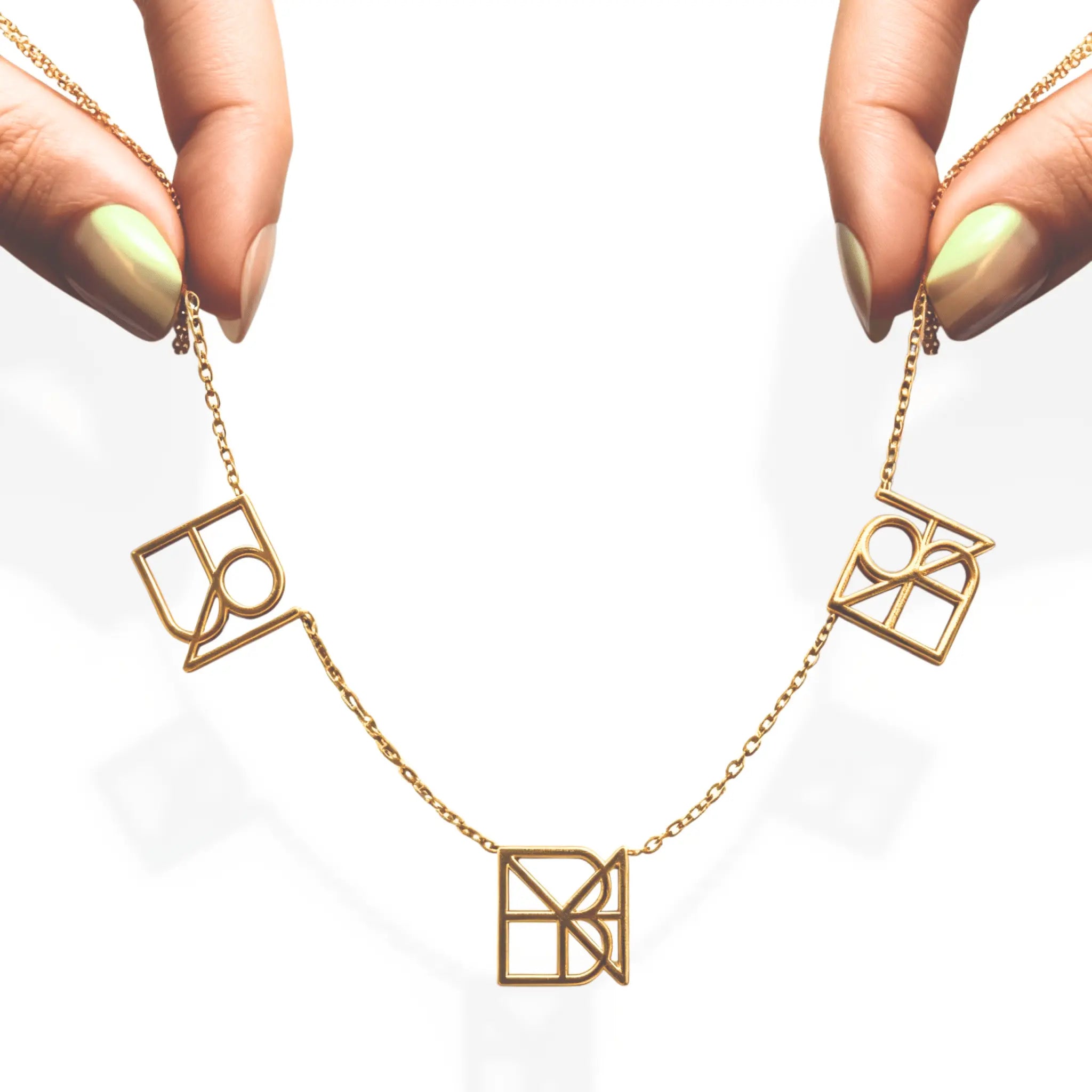 danibydsgn three symbol necklace held up by elegant fingers – personalized 9k yellow gold triple pendant necklace, luxury custom name necklace, bespoke custom jewelry