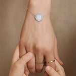 Close-up of a hand wearing the Danibydsgn Two Fingerprint Coin Bracelet in 925 Sterling Silver, held gently by a child’s hands — symbolising love, connection, and the lasting bond between generations.