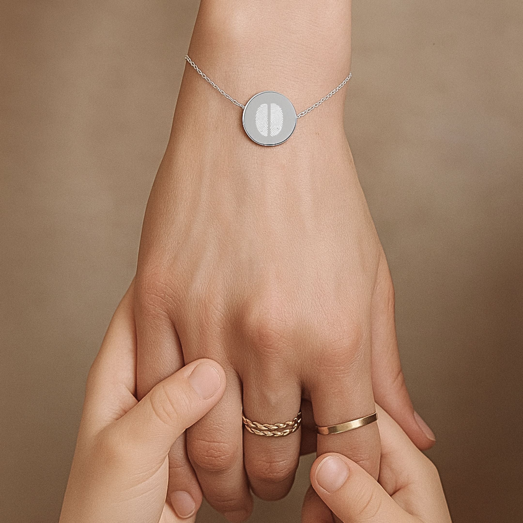 Close-up of a hand wearing the Danibydsgn Two Fingerprint Coin Bracelet in 925 Sterling Silver, held gently by a child’s hands — symbolising love, connection, and the lasting bond between generations.