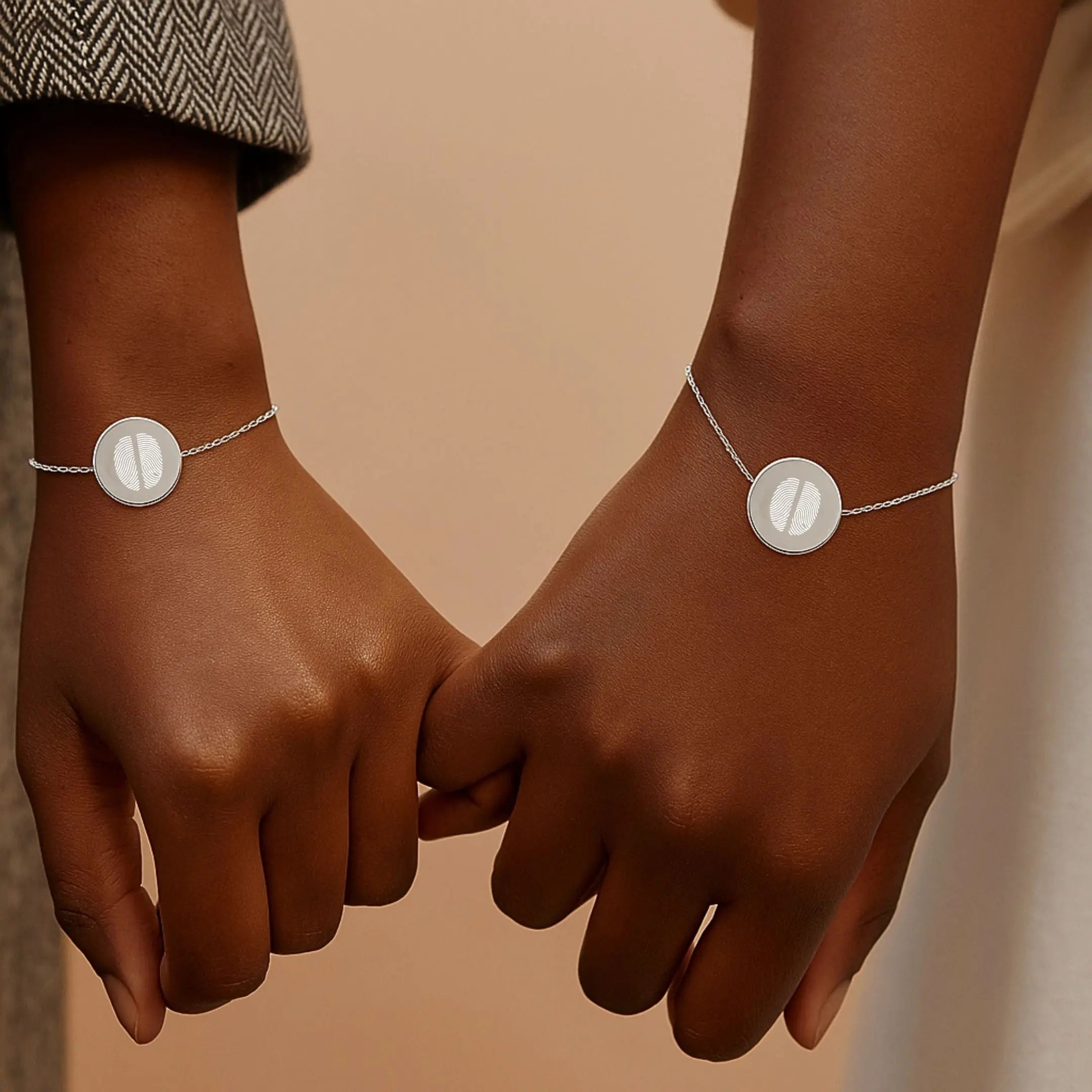 Two hands wearing matching Danibydsgn Two Fingerprint Coin Bracelets in 925 Sterling Silver, featuring engraved dual fingerprints on polished pendants — symbolising love, connection, and timeless togetherness.