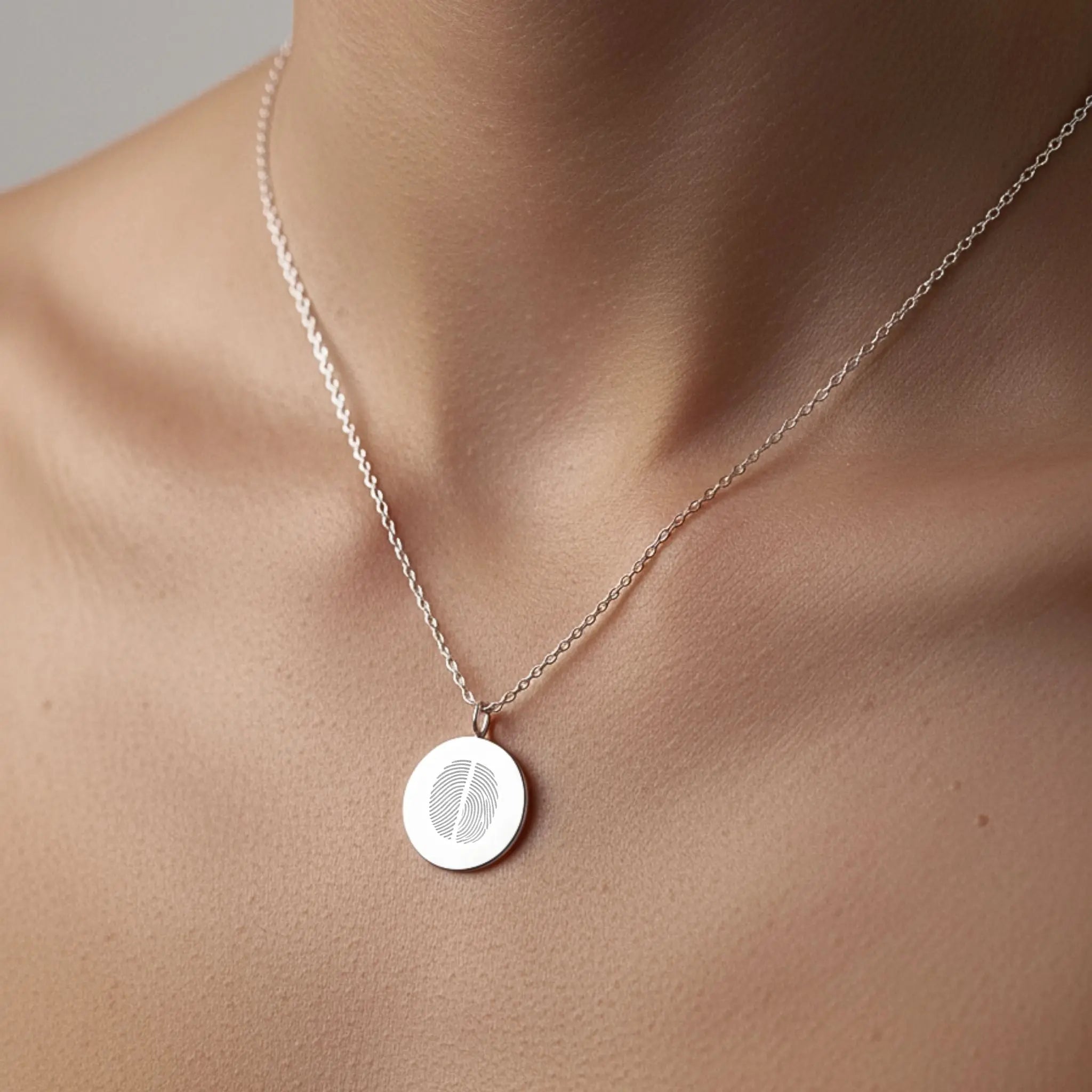 Model wearing a Danibydsgn two fingerprint coin necklace in 925 sterling silver, showcasing its elegant design.
