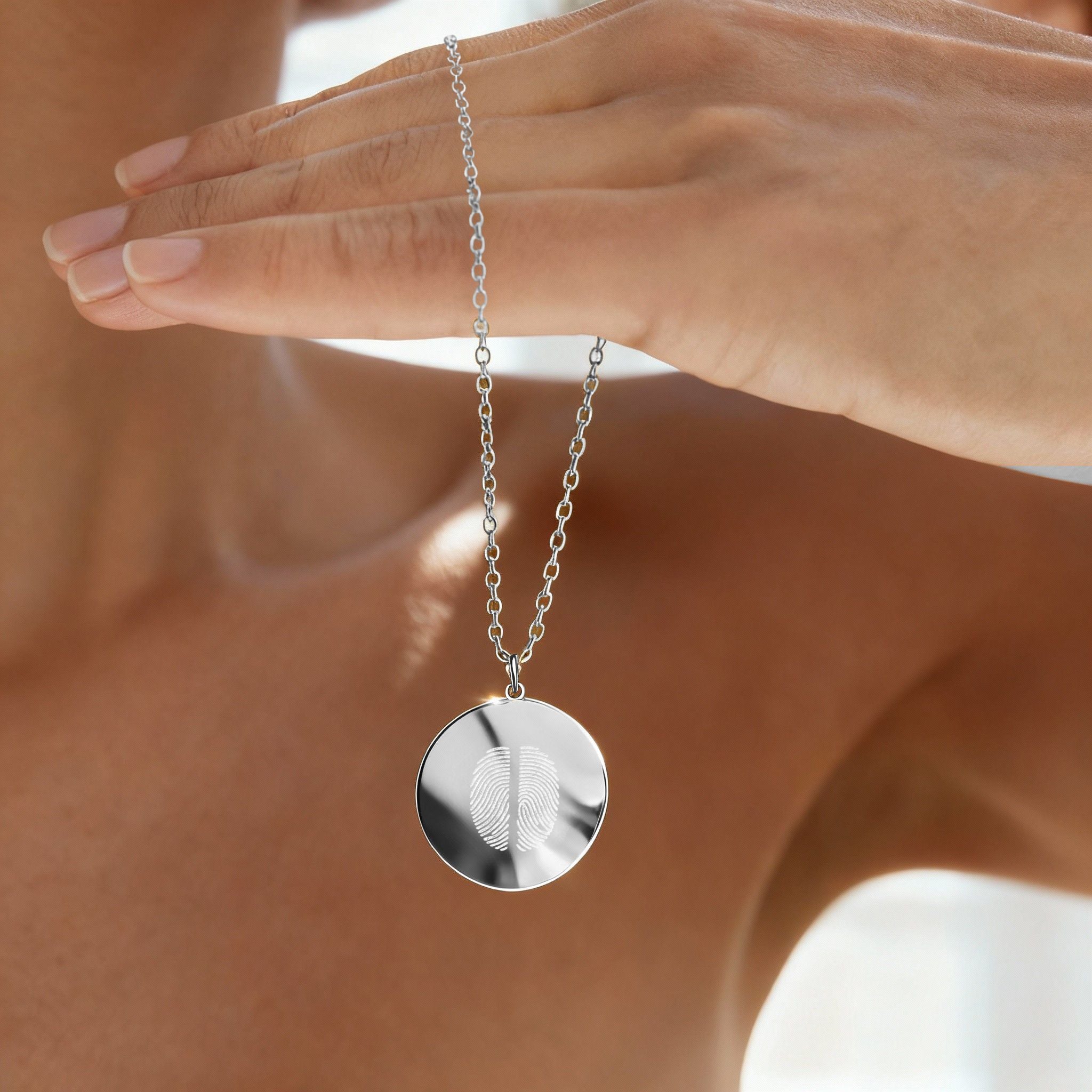 Model holding the Danibydsgn Two Fingerprint Pendant Necklace in 925 Sterling Silver, showing its reflective finish and intricate dual fingerprint engraving — a luxurious keepsake symbolizing lasting love and connection.