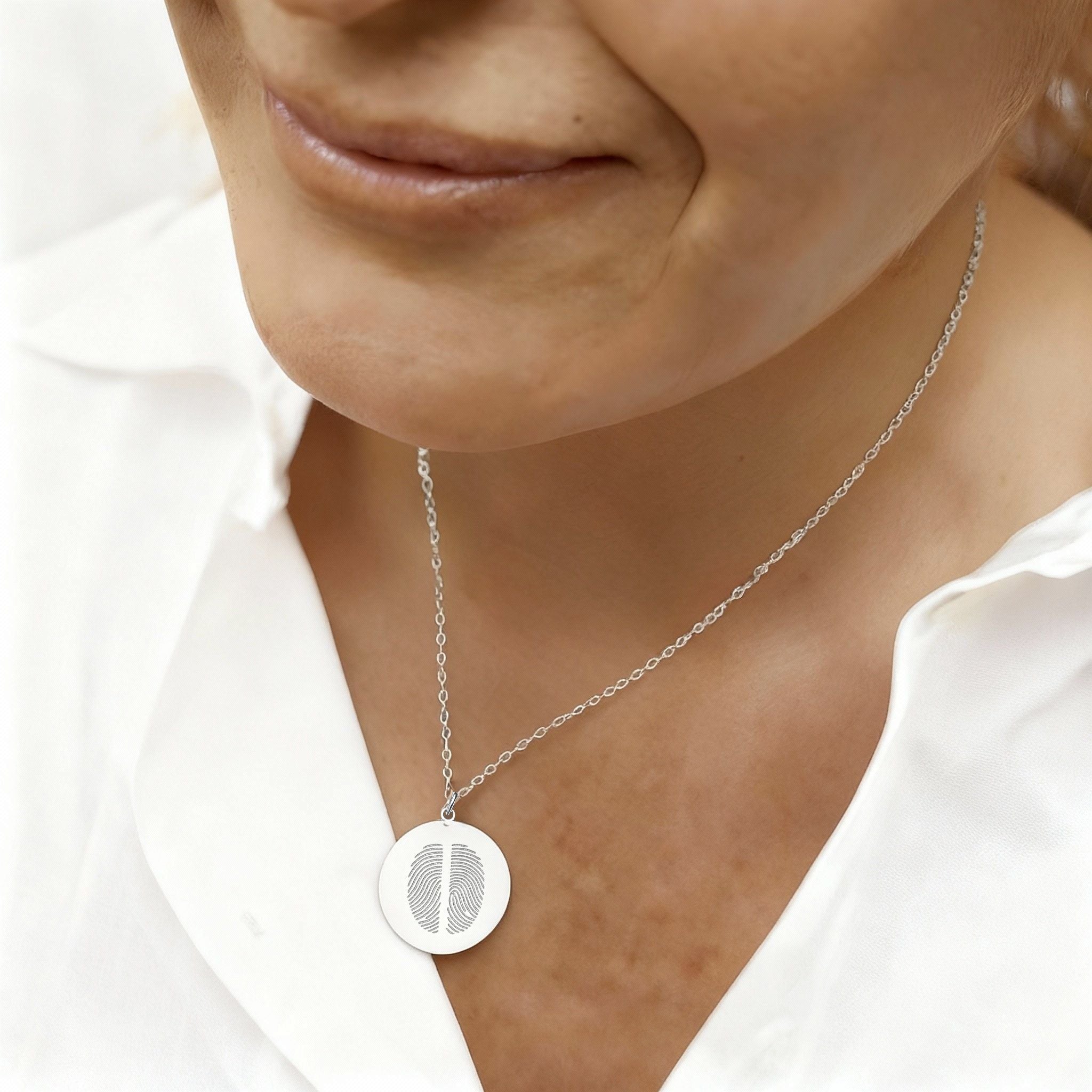 Close-up lifestyle image of the Danibydsgn Two Fingerprint Pendant Necklace in 925 Sterling Silver, worn with a white blouse — a polished, elegant keepsake capturing two fingerprints as a symbol of love and connection.