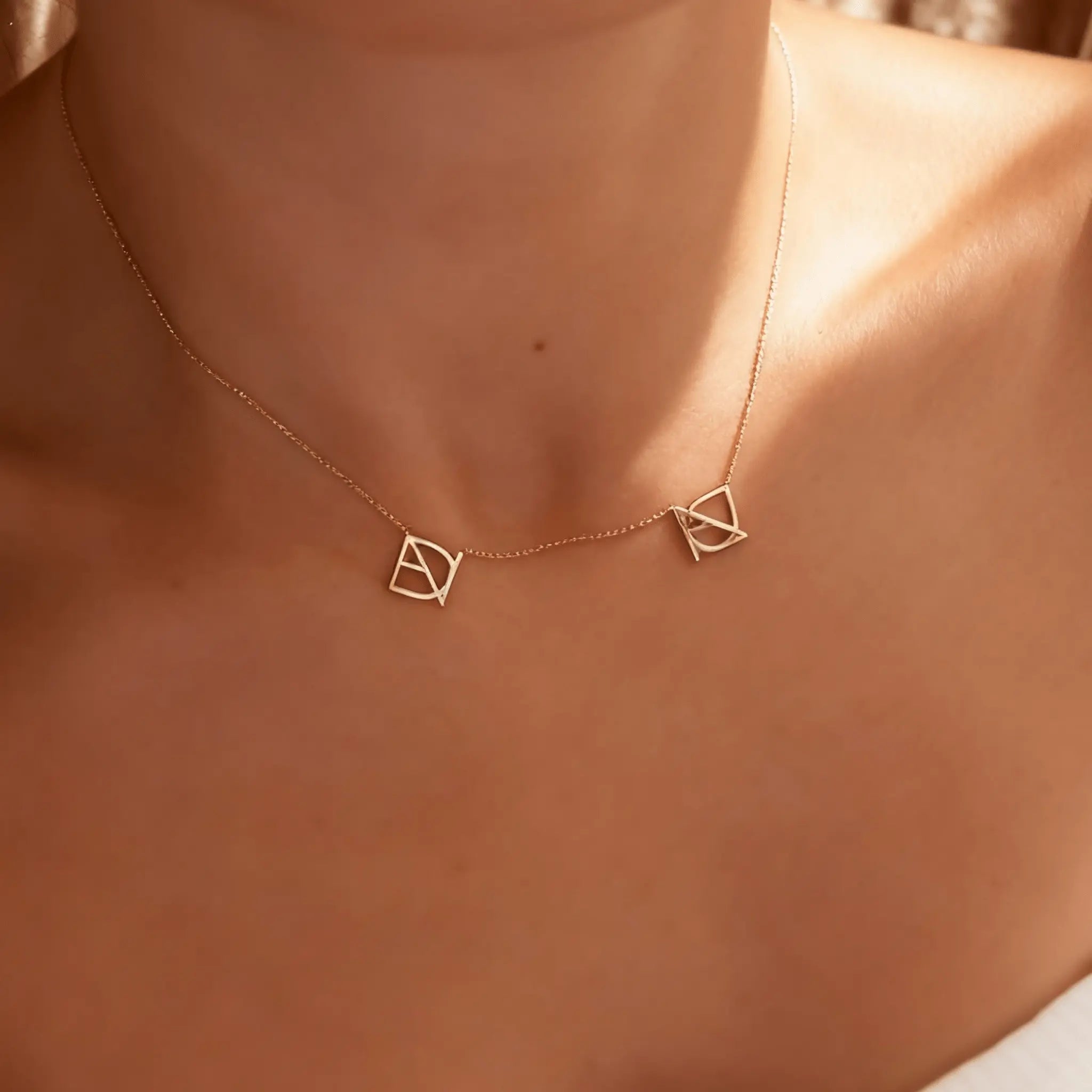 DaniByDsgn two symbol necklace worn on the neck by a lady– personalized 9k yellow gold double symbol pendant, luxury bespoke custom jewelry
