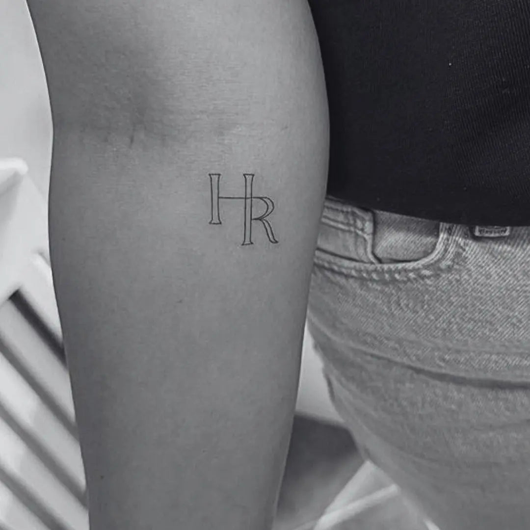 Fine line initial monogram tattoo design by Danibydsgn, showcasing a minimalist and elegant style.