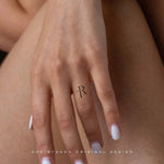 Close-up of a delicate 'TR' Custom Initial Monograms tattoo on a hand, exemplifying Danibydsgn's custom logo design tailored for personal branding, body art and tattoo design. This minimalist name monogram serves as a subtle expression of identity, blending and personal branding.   