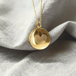 Close-up of the Heart Fingerprint Coin Pendant Necklace in 18K Gold Vermeil by Danibydsgn resting on soft fabric. The pendant features two fingerprints engraved in a heart shape, symbolising eternal love and connection. A luxury personalised necklace crafted with precision and modern elegance.