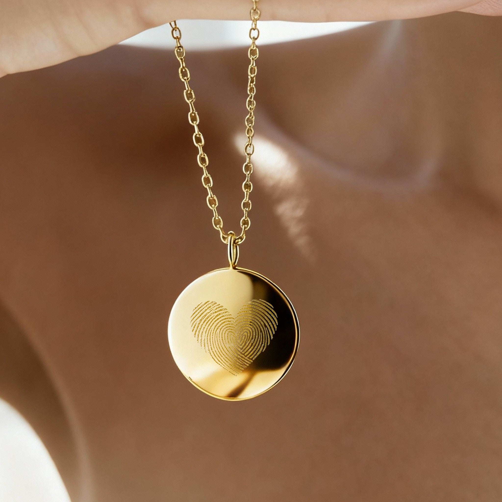 Luxury Heart Fingerprint Coin Necklace in 18K Gold Vermeil by Danibydsgn shown in natural light, featuring two overlapping fingerprints forming a heart shape. A meaningful keepsake necklace symbolising love and connection, crafted with precision engraving and a radiant gold finish for an elegant, timeless look.
