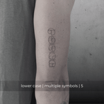 A minimalistic fine line tattoo of an overlapping Custom Logos design on a person's outer arm of a five symbol design in lowercase letters, exemplifying custom logo design, name tattoo design, and body art. This simple tattoo idea showcases personal branding and tattoo art, ideal for both name logos and wall art applications.