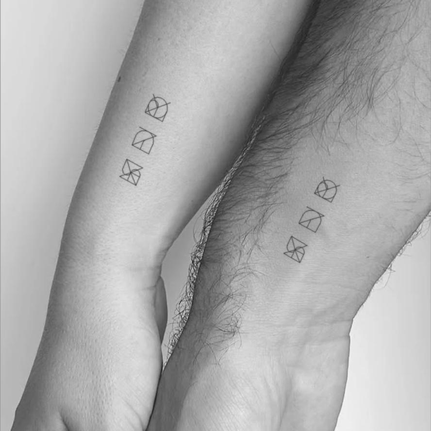 Matching minimalist flash tattoo designs by Danibydsgn, featuring premade English quote-inspired logo symbols inked on two wrists, showing the clean, balanced linework and modern design style.