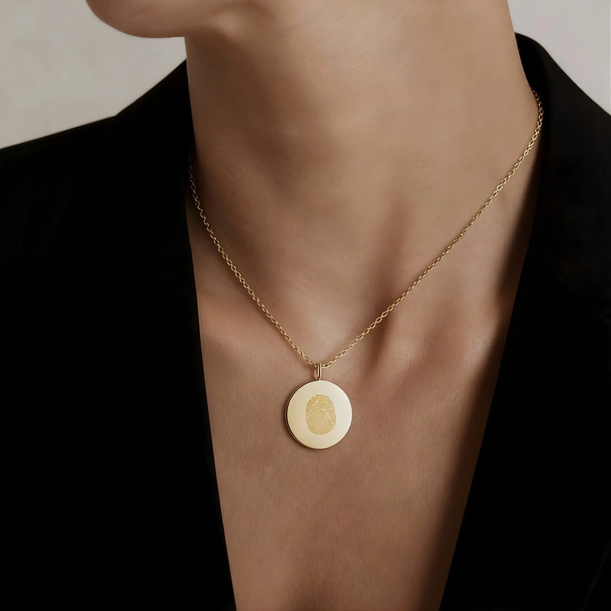 Model wearing a single fingerprint coin necklace in 18k gold vermeil by Danibydsgn, showcasing its elegant design.