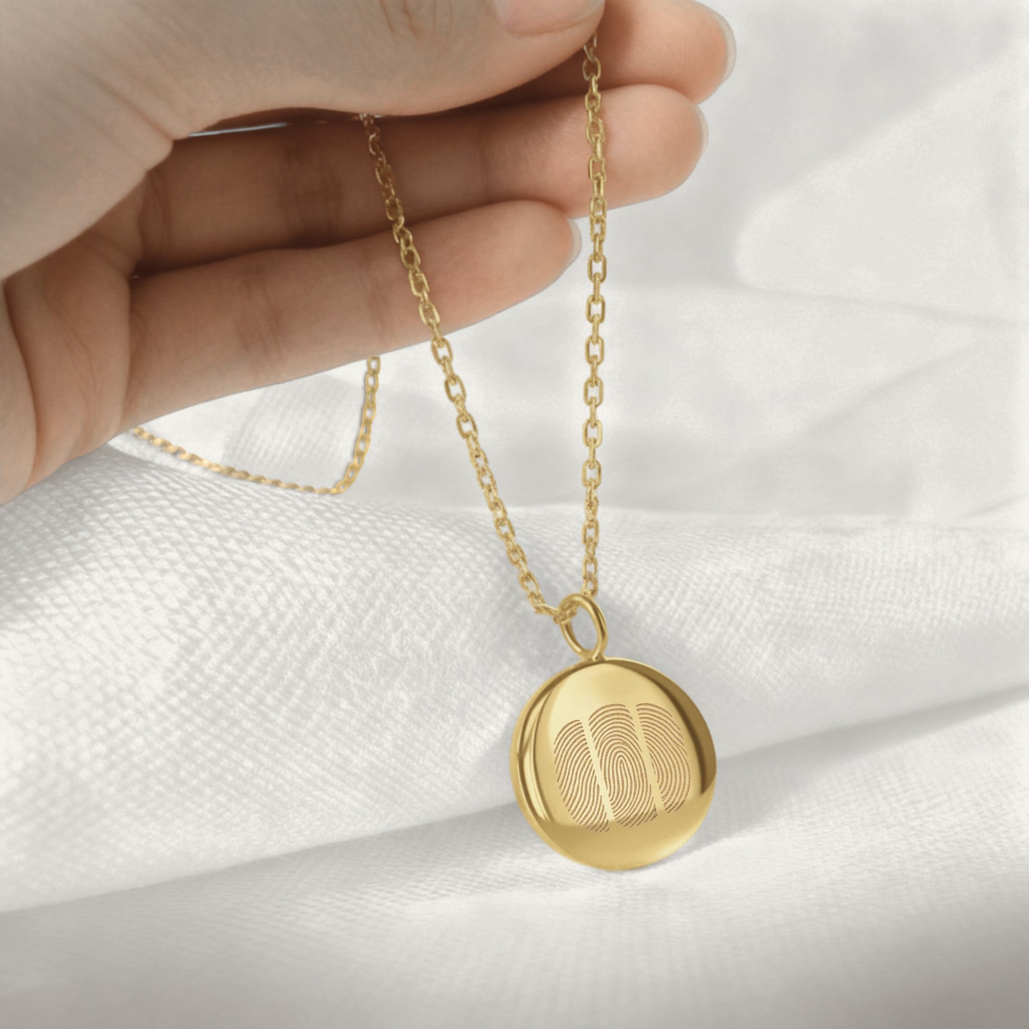 Hand holding the Luxury Three Fingerprint Coin Necklace in 18K Gold Vermeil by Danibydsgn. Features three delicately engraved fingerprints on a radiant gold pendant, symbolizing family bonds and connection. A timeless, personalized keepsake handcrafted for elegance and meaning.