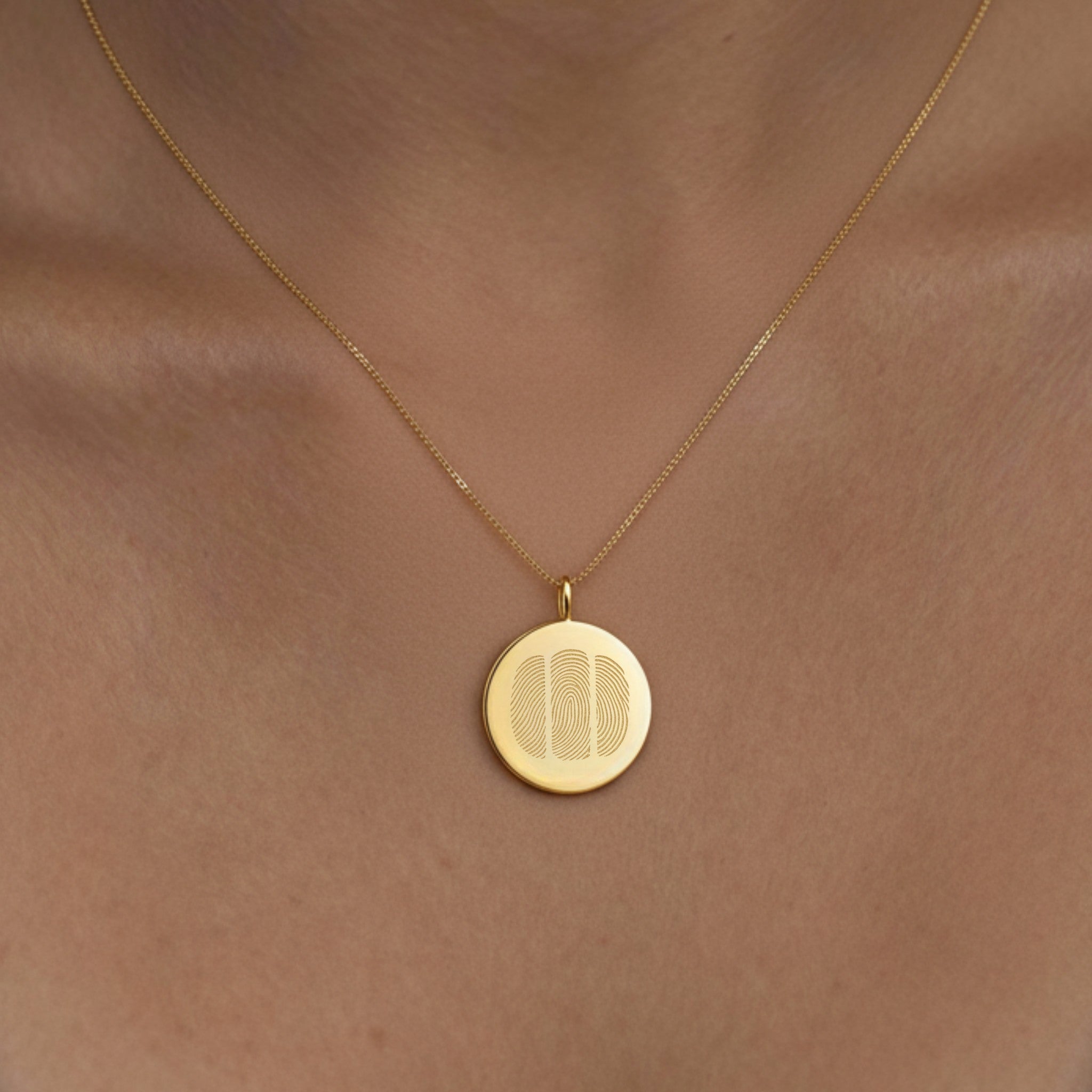 Model wearing the Luxury Three Fingerprint Coin Necklace in 18K Gold Vermeil by Danibydsgn. The engraved triple fingerprint design sits elegantly against the skin, symbolizing lasting connection and love. A modern, personalized heirloom crafted in radiant gold vermeil for everyday luxury.