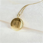 The Luxury Three Fingerprint Coin Necklace in 18K Gold Vermeil by Danibydsgn rests elegantly on a white fabric background. Featuring three detailed fingerprints engraved into a polished gold pendant, this handcrafted piece symbolizes love, memory, and connection in timeless luxury jewelry design.