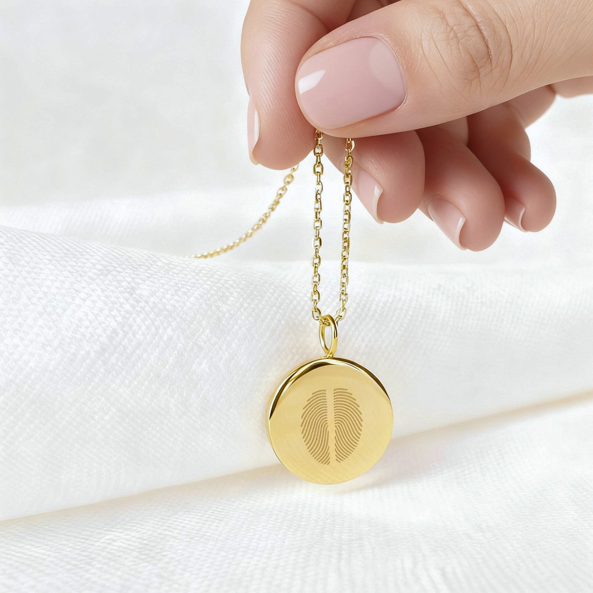 Handheld two fingerprint pendant necklace in 18K gold vermeil by Danibydsgn, featuring dual engraved fingerprints on a polished round disc. A luxury, sentimental keepsake celebrating meaningful connections, handcrafted for timeless elegance and personalization.