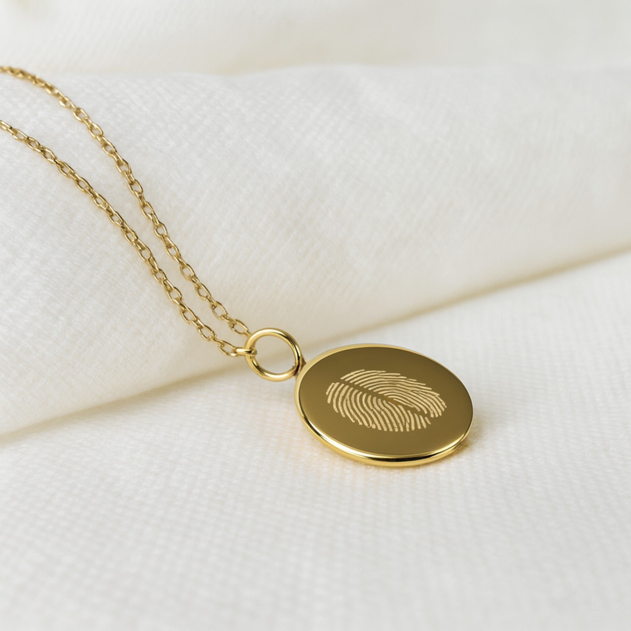 Close-up of the Two Fingerprint Pendant in 18K gold vermeil by Danibydsgn. Features finely engraved dual fingerprints on a smooth round disc with a delicate gold chain — a personalized luxury necklace representing love, connection, and individuality.