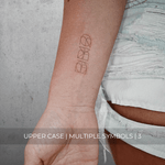 A minimalistic fine line tattoo of an overlapping Custom Logos design on a person's inner arm of a three symbol design in uppercase letters, exemplifying custom logo design, name tattoo design, and body art. This simple tattoo idea showcases personal branding and tattoo art, ideal for both name logos and wall art applications.