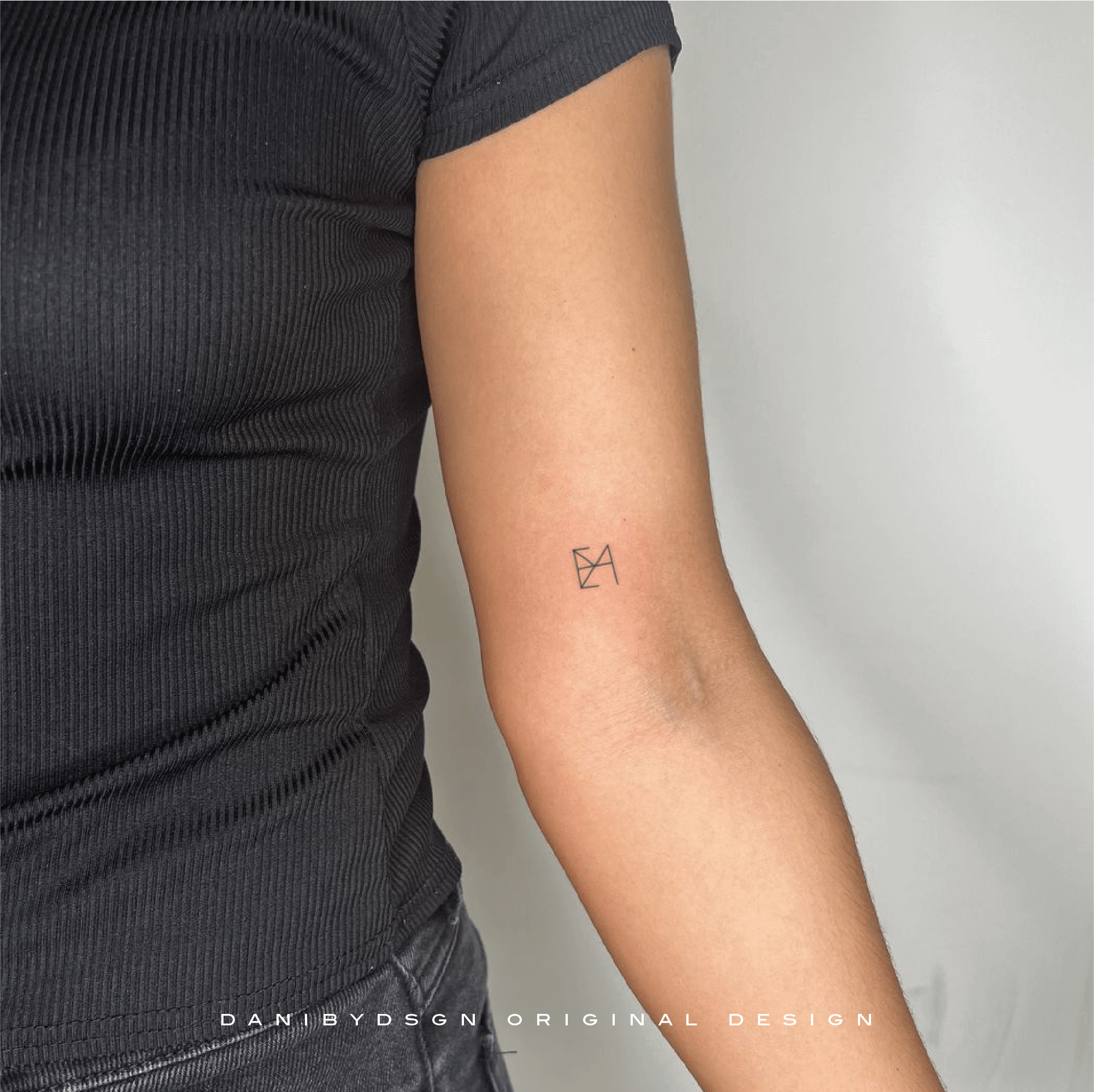 Minimalist name logo design used as a fineline tattoo on the forearm, reflecting the unique overlapping logo design by Danibydsgn, renowned for bespoke name tattoo design. This subtle body art represents the essence of name logos and is an inspiration for simple tattoo ideas, embodying the brand’s expertise in name logo design.  Danibydsgn is the original name logo creator with 30,000 personalized designs completed worldwide and over 1,700+ five star reviews. 