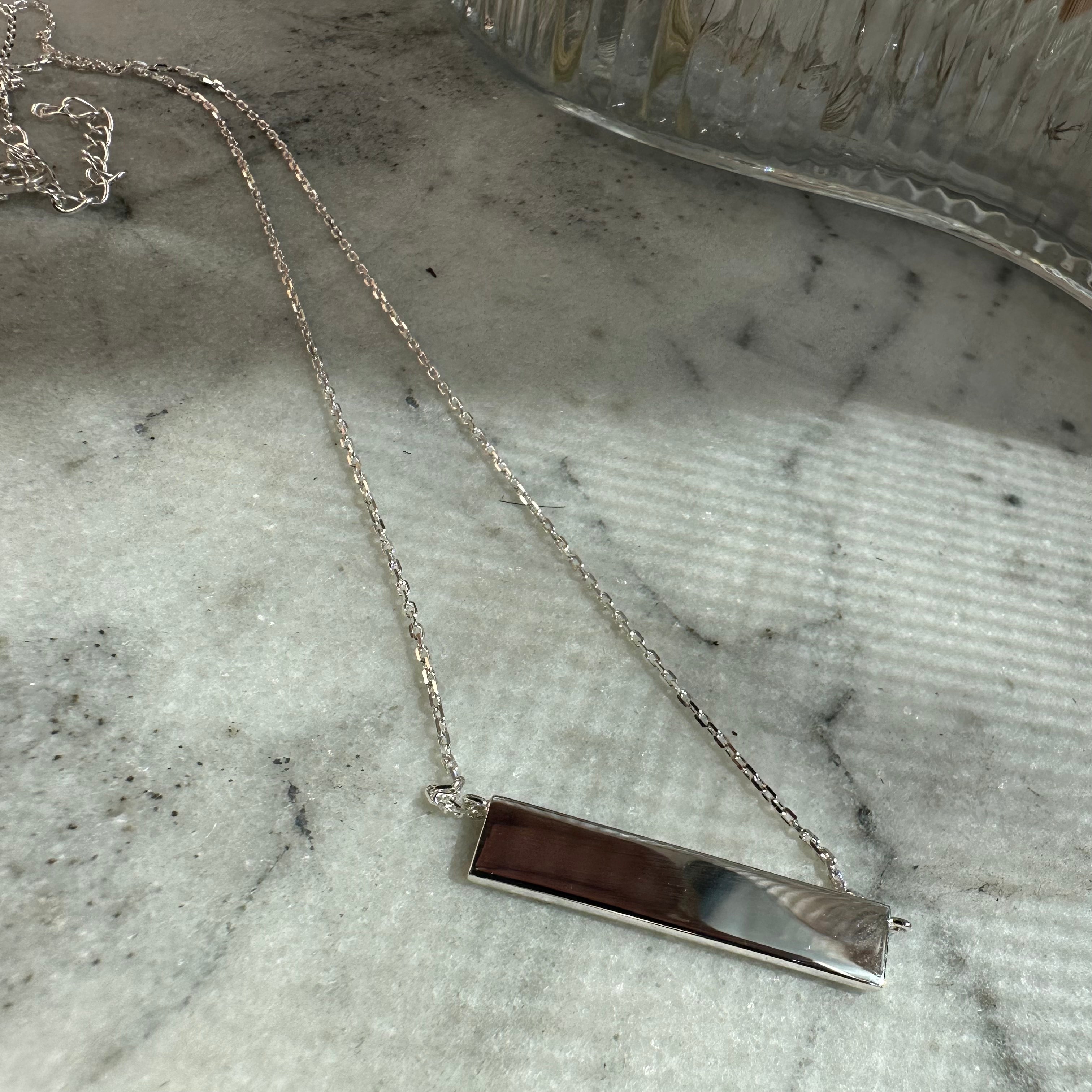 Our Sterling Silver Bar Necklace is a sleek and contemporary piece that's waiting to be personalized with a signature Danibydsgn custom logo design. This engravable silver bar necklace offers a polished canvas for your unique expression. A customizable piece of personalized jewelry, not only adds a touch of minimalist luxury to your collection but also serves as a bespoke gift.   It's not just a keepsake jewelry piece—it's a statement of personal branding and a cherished jewelry gift.